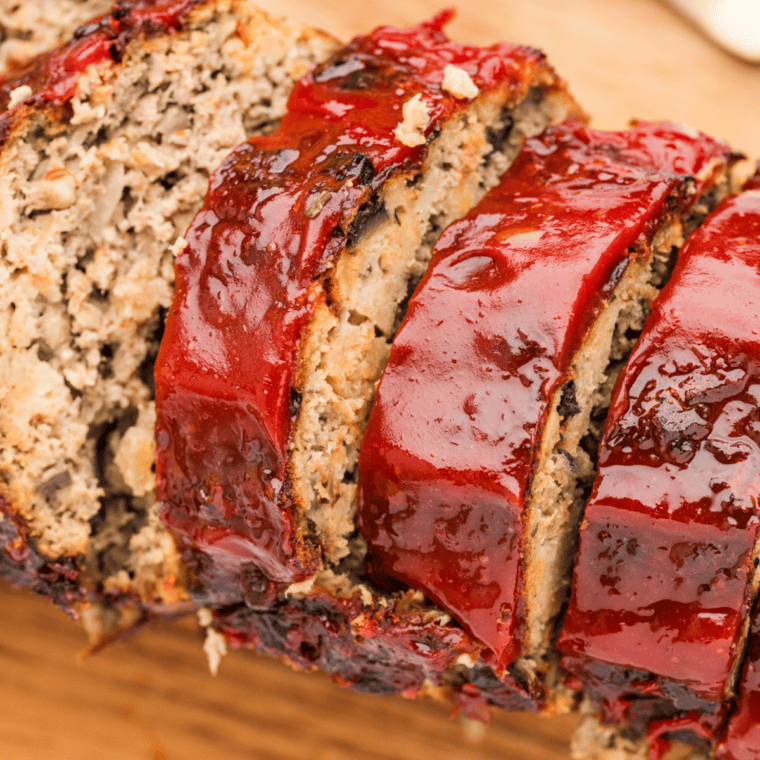 One pound meatloaf sliced on a cutting board showing a juicy, tender interior with a rich glaze on top.