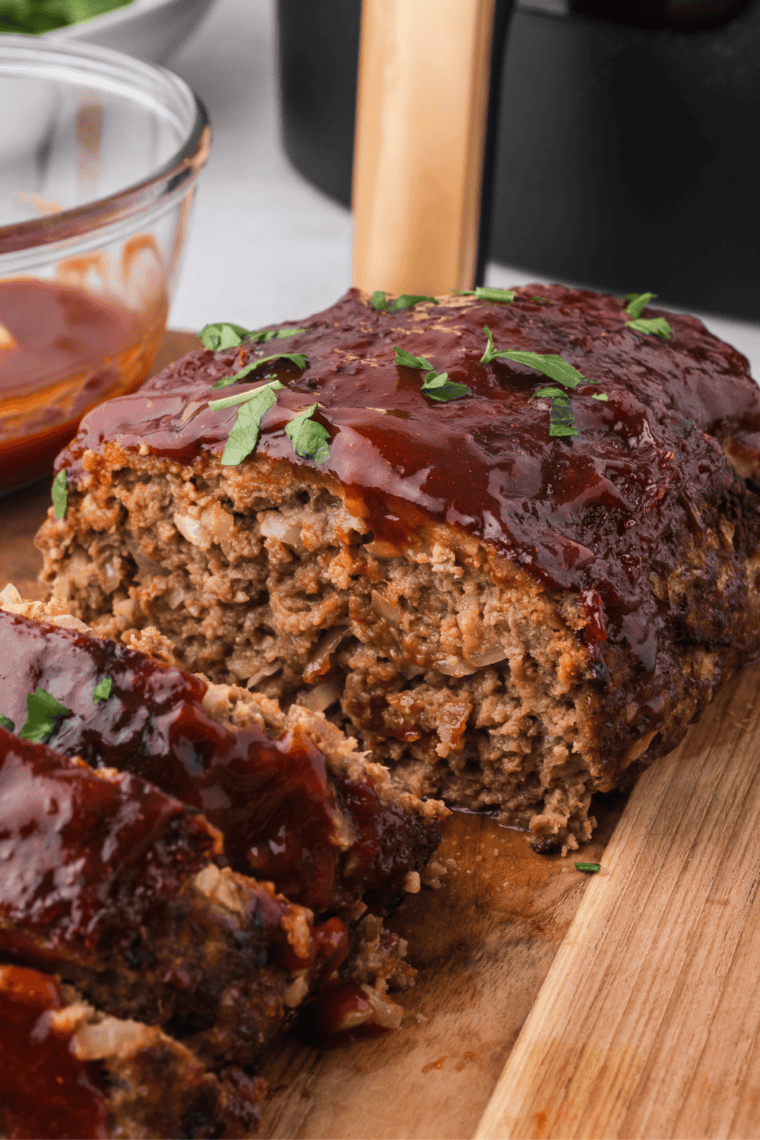 One pound meatloaf served with a caramelized top crust and fresh parsley garnish on a dinner plate.