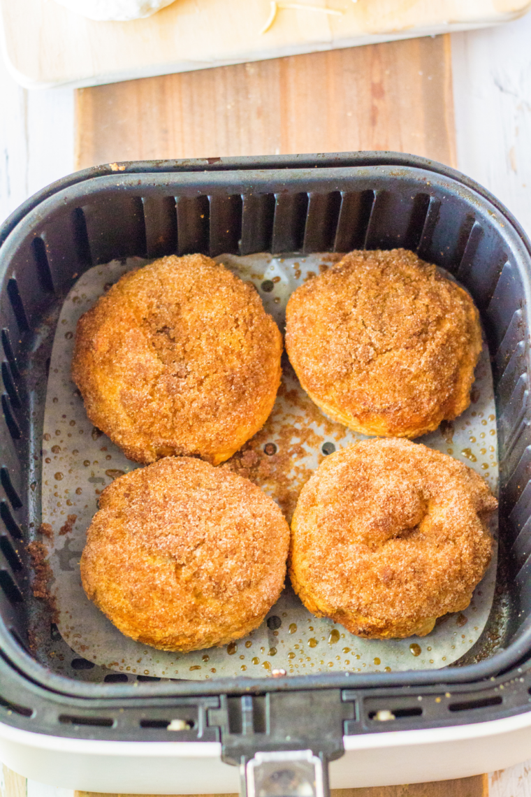 Air fryer method for cinnamon crunch bagels showing bagels placed on parchment in the basket, then air fried at 350°F until golden brown and finished cooling on a wire rack.