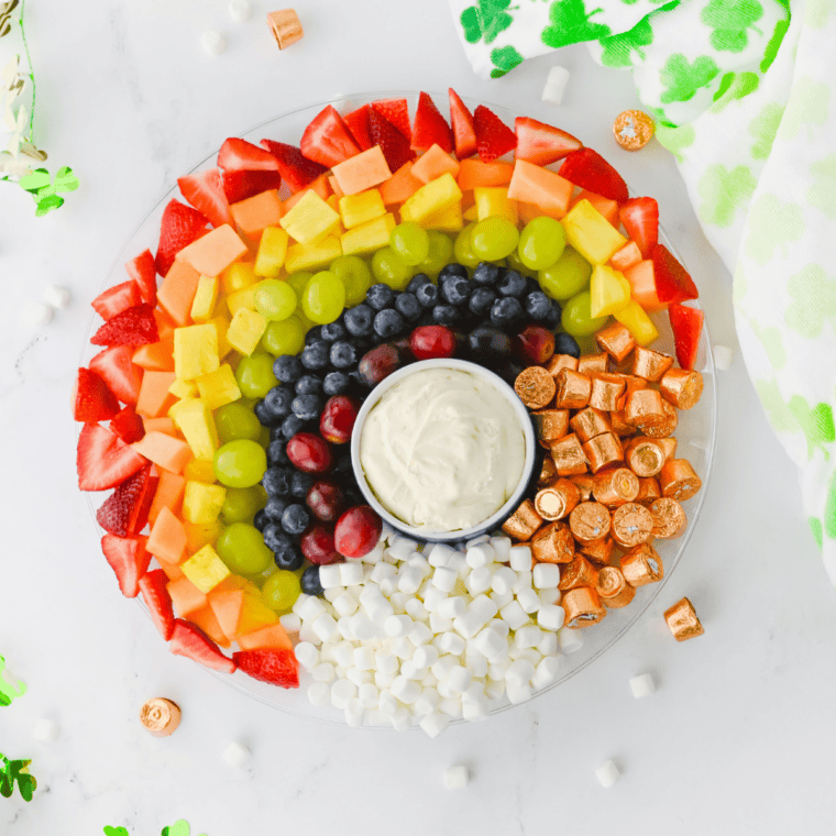 Overhead view of a rainbow fruit platter with strawberries, cantaloupe, pineapple, grapes, and blueberries