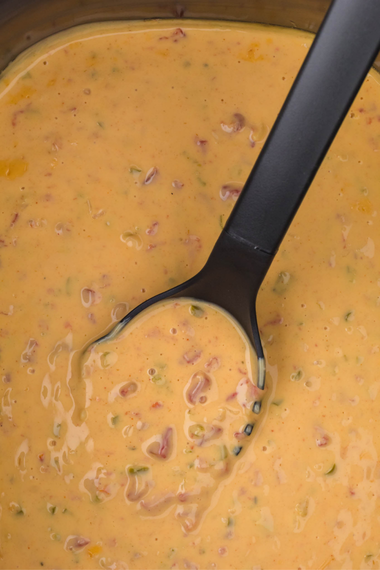 Bowl of slow cooker Velveeta queso served with a spoon in rich creamy melted cheese dip.
