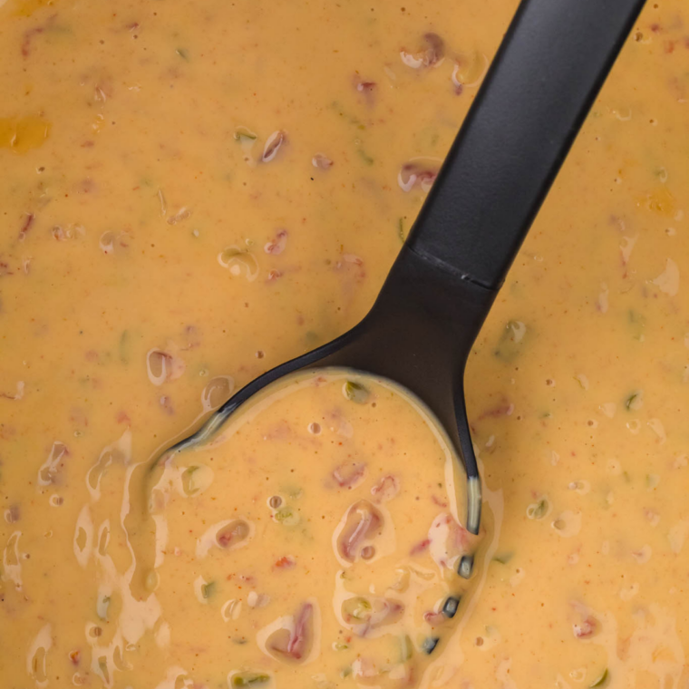 Bowl of slow cooker Velveeta queso with spoon serving creamy melted cheese dip
Close up of cheesy Velveeta queso in bowl with spoon ready for dipping