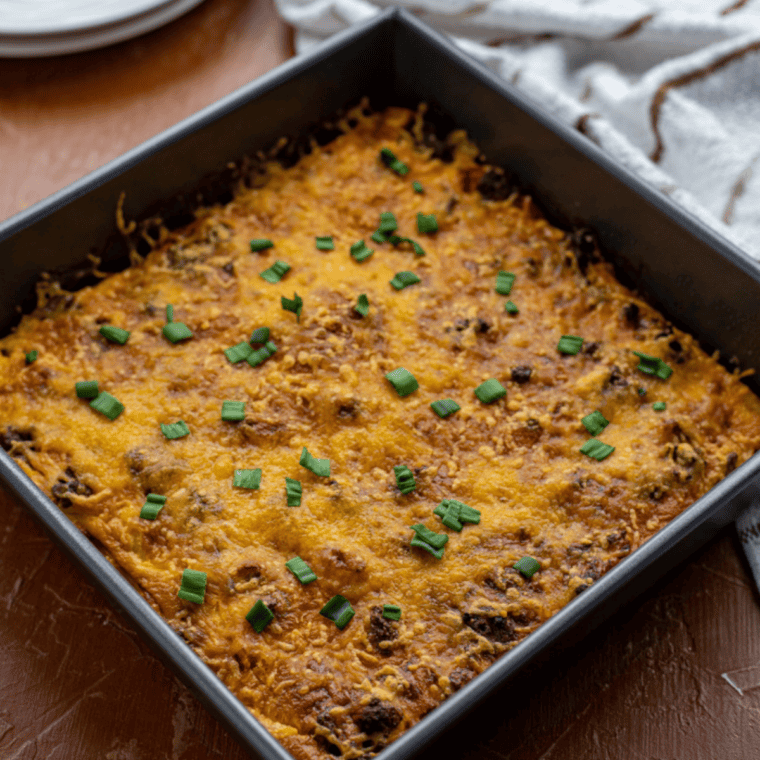 Baked venison casserole topped with bubbly melted cheddar cheese in a cast iron skillet