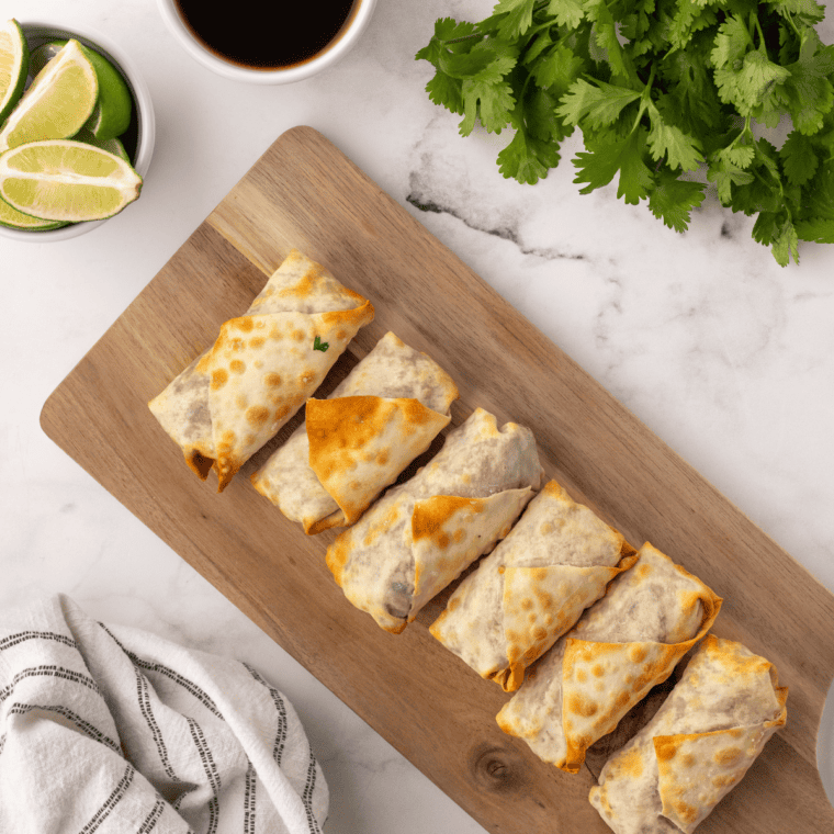 A plate of crispy air fryer birria egg rolls served with consommé.