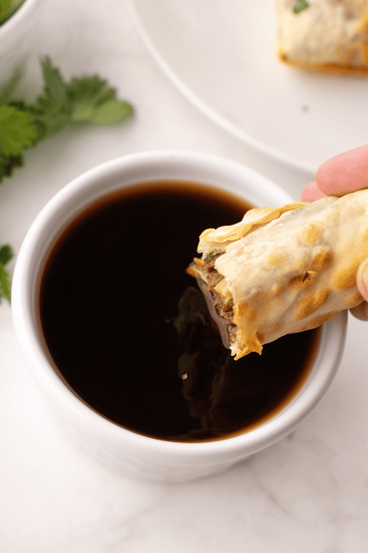 Beef birria egg roll cut in half showing shredded beef and melted cheese filling