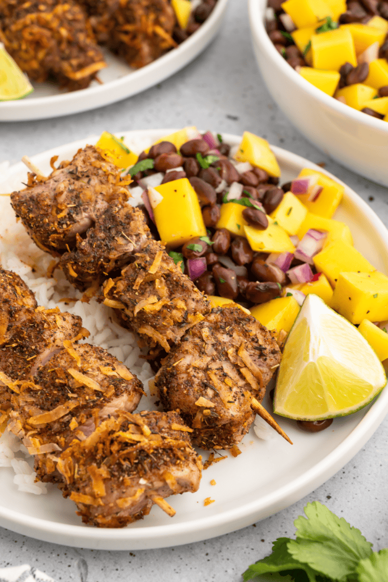 Caribbean jerk pork tenderloin skewers topped with fresh mango black bean salsa