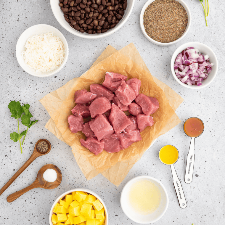 Ingredients for air fryer jerk pork skewers including pork tenderloin, mango, black beans, and jerk seasoning.