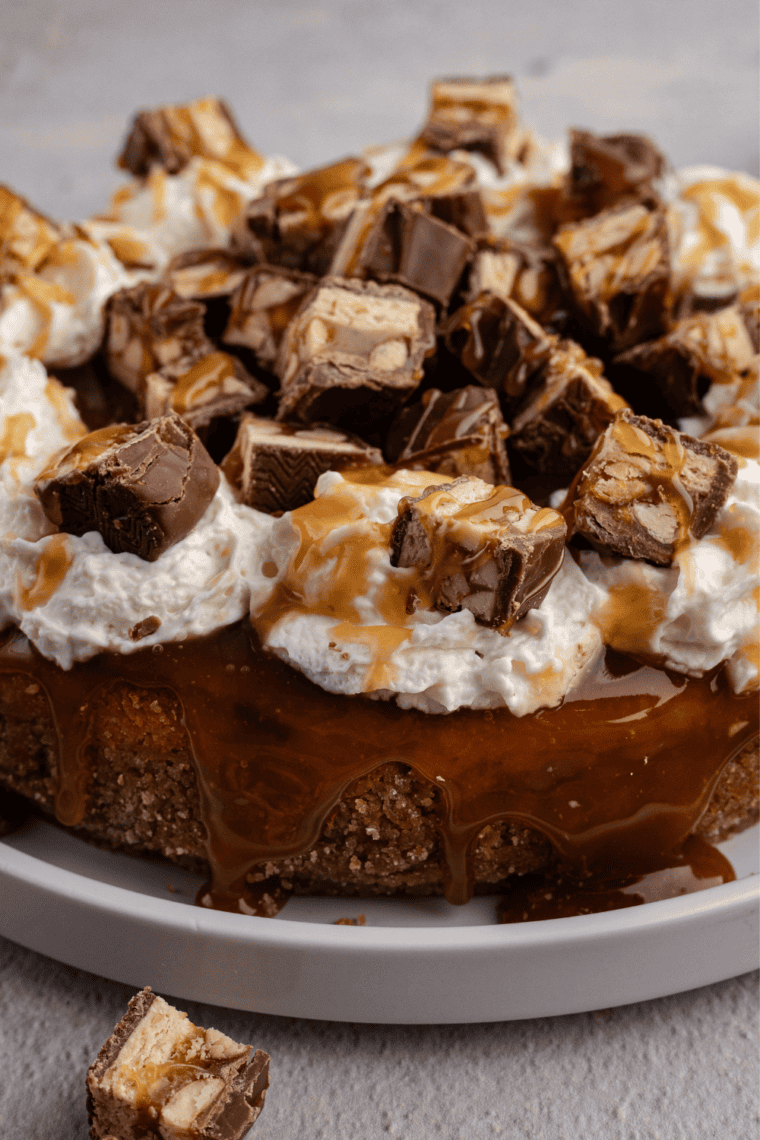 Close-up slice of air fryer Snickers cheesecake showing the graham crust and creamy filling