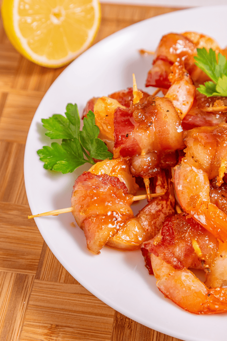 Plate of crispy jalapeño popper shrimp wrapped in bacon, garnished with parsley