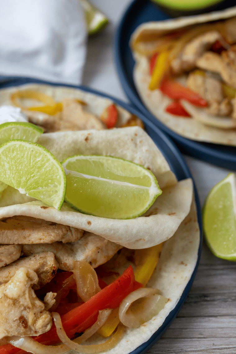 Sizzling Blackstone chicken fajitas served on a wooden board with lime wedges and cilantro