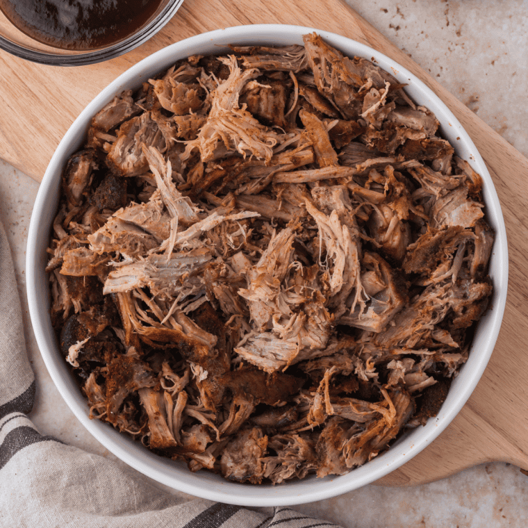 Shredded smoked pulled pork in a white bowl seasoned with copycat Jack Daniel's pork rub