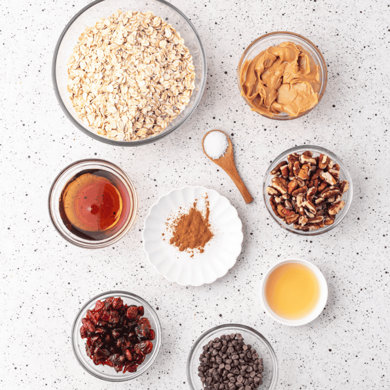 Rolled oats, multigrain blend, nuts, honey, and maple syrup laid out for homemade granola clusters