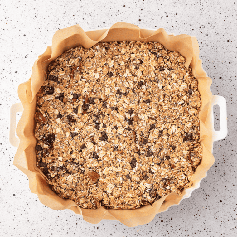 Granola mixture pressed into a firm, even layer on parchment to form clusters