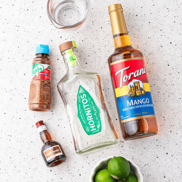 Three tequilas, Grand Marnier, limes, and agave laid out to make a copycat margarita