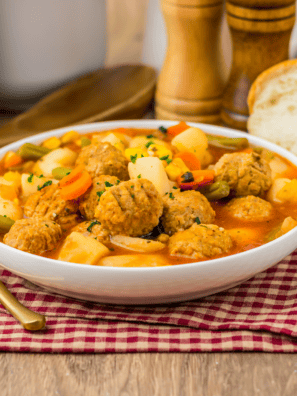 Bowl of slow cooker meatball vegetable soup with potatoes, carrots, and green beans, topped with fresh parsley