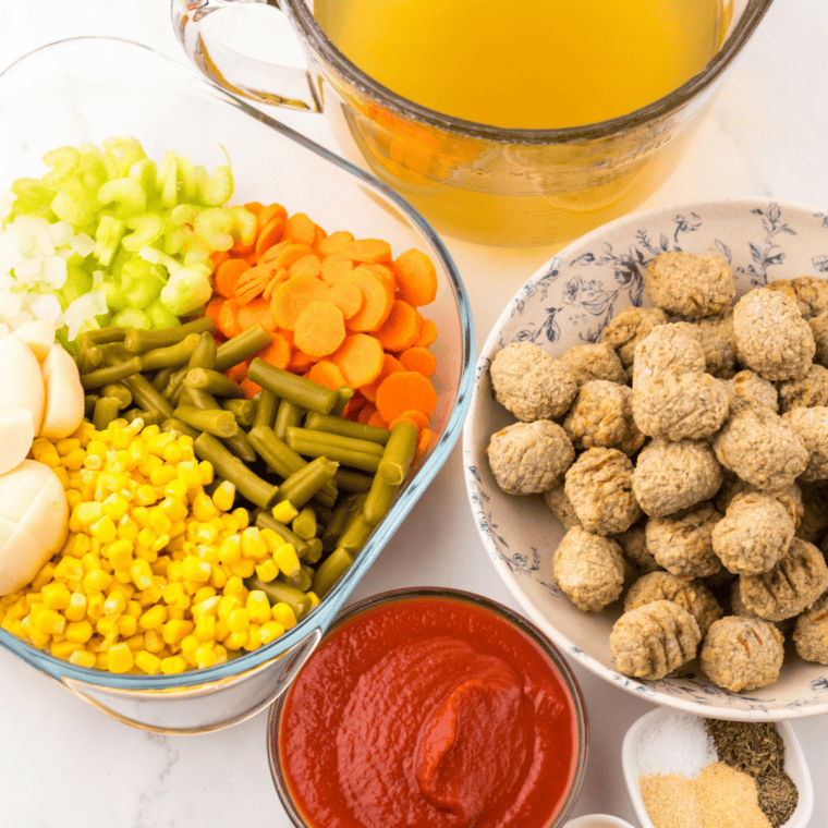 Ingredients for slow cooker meatball vegetable soup, including frozen meatballs, potatoes, carrots, broth, and canned vegetables