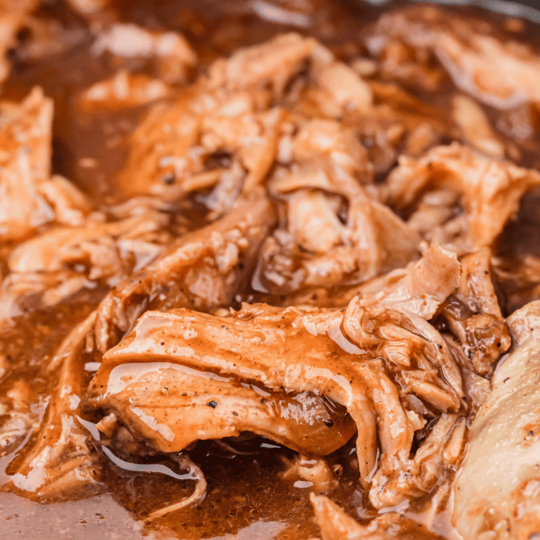 Close-up of saucy Jack Daniel's pulled pork in the crock pot coated in whiskey BBQ sauce