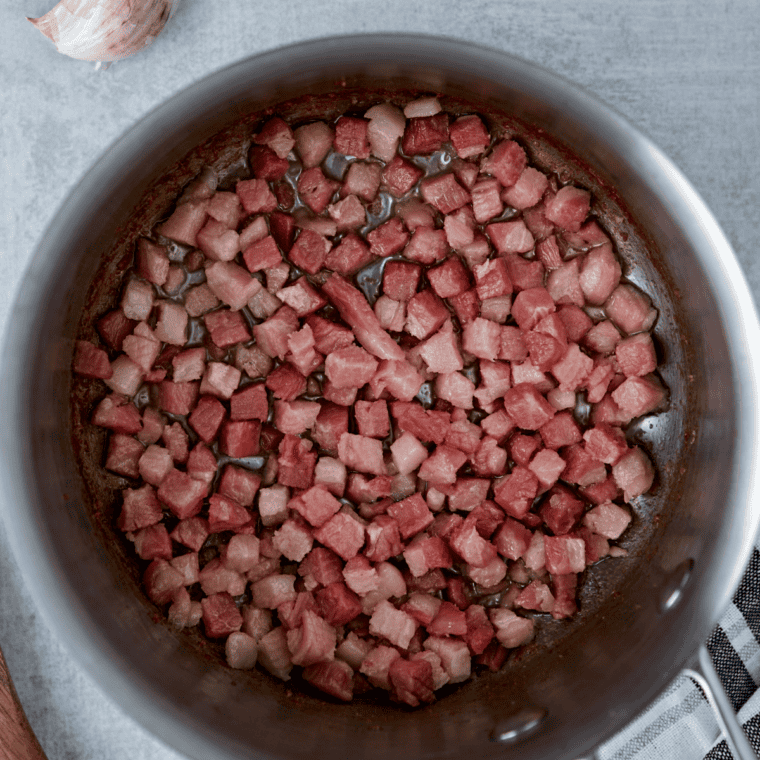Chopped bacon crisping in a cast iron skillet