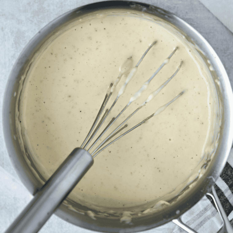 Shredded cheddar and gouda melting into the creamy sauce