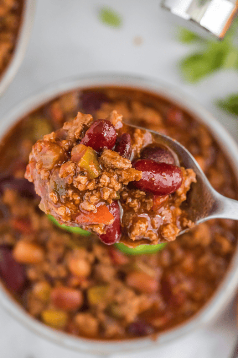 mccormick chili recipe in a white bowl topped with shredded cheddar and sour cream