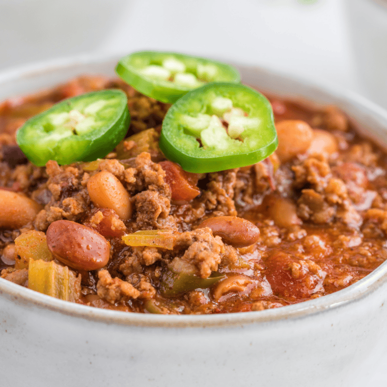 Bowl of McCormick chili topped with sliced jalapeños, featuring a hearty blend of seasoned ground beef, beans, and rich tomato sauce, served hot and ready for dinner.