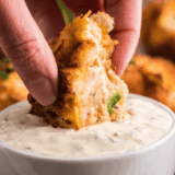 Golden fried hush puppy being dipped into creamy McCormick Mayonesa con limón