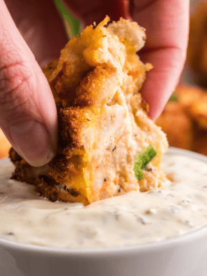 Golden fried hush puppy being dipped into creamy McCormick Mayonesa con limón