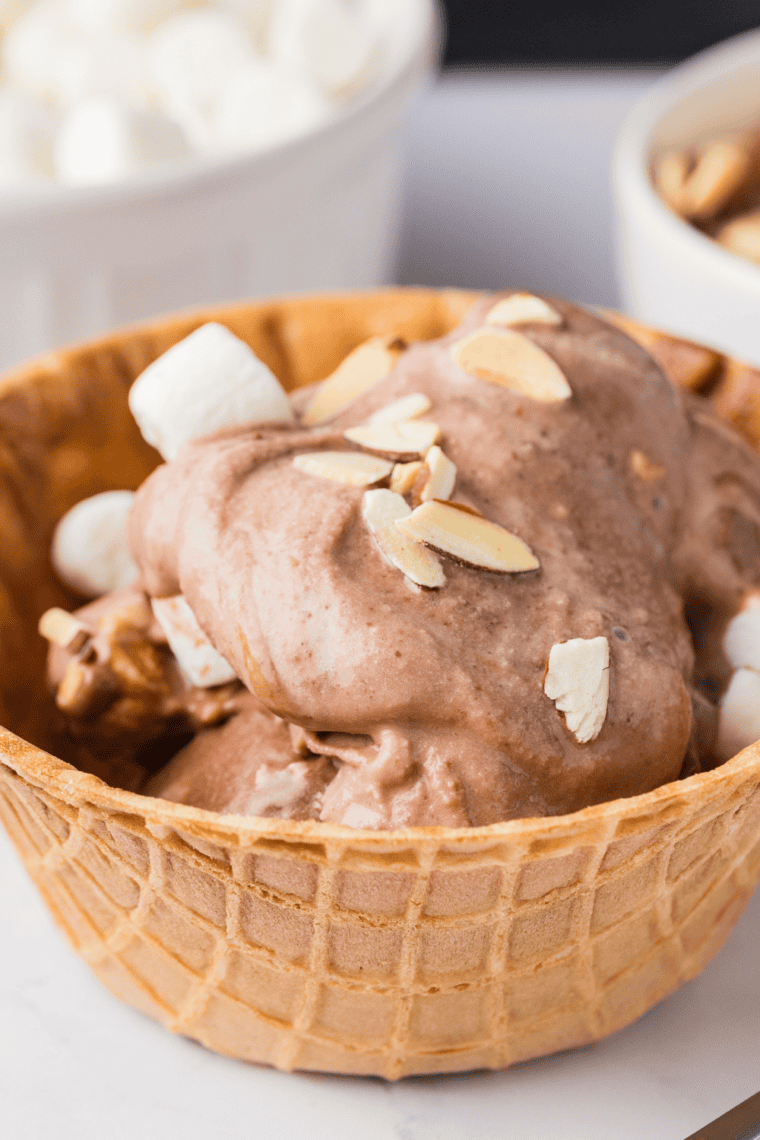 Scoop of Ninja Creami copycat Blue Bell Rocky Road in a bowl topped with mini marshmallows and roasted almonds