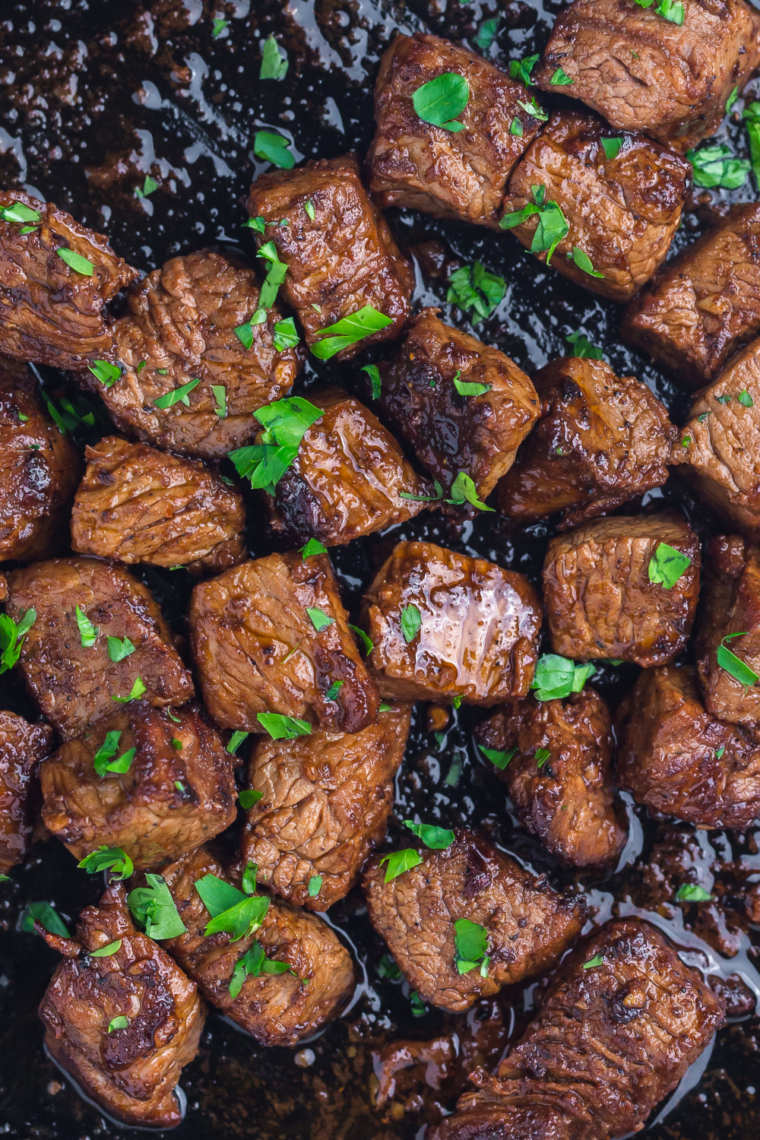 Close-up of crispy seasoned steak bites cooked in a Ninja Crispi and garnished with fresh parsley.