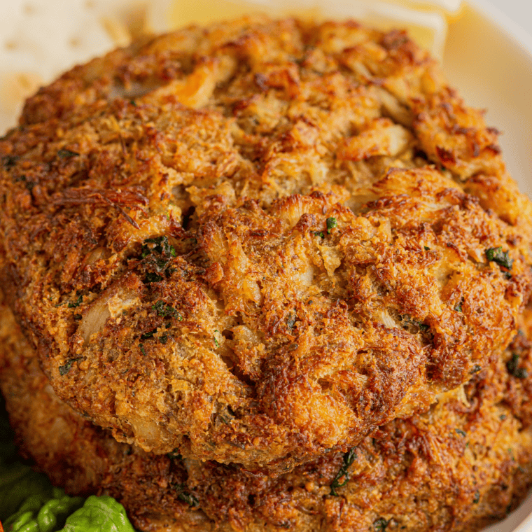 Ruth's Chris crab cakes on a plate with lemon wedges and parsley.