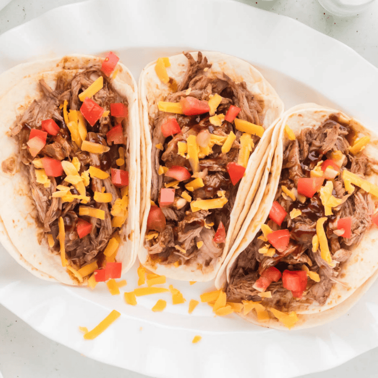 Soft tacos filled with seasoned Cuban shredded pork and lime