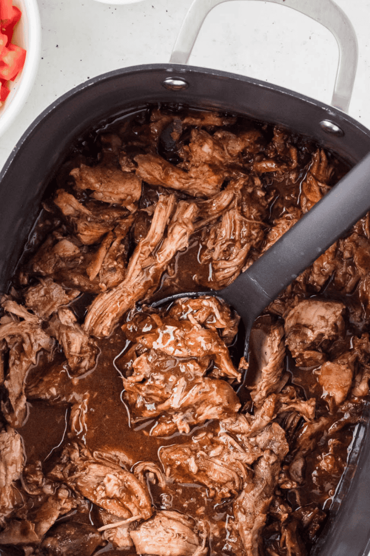 Shredded pulled pork coated in Jack Daniel's sauce inside a slow cooker