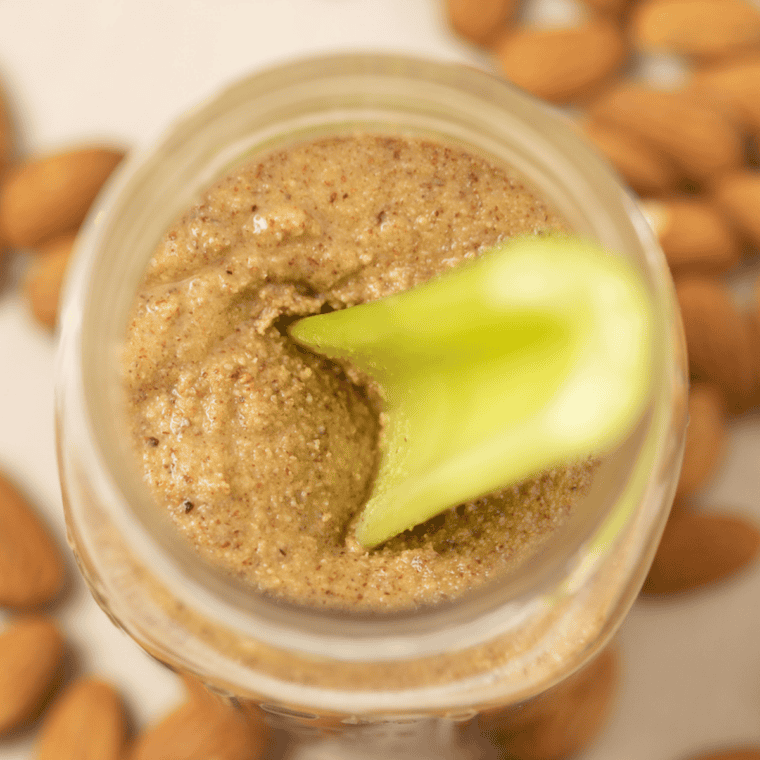 Celery stick dipping into a jar of homemade almond butter