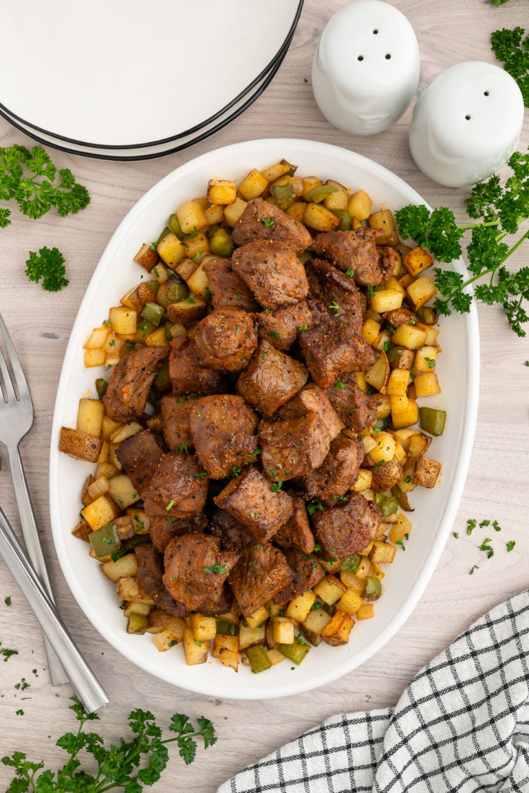 Juicy medium-rare sirloin steak bites and crispy roasted potato cubes served on a white plate