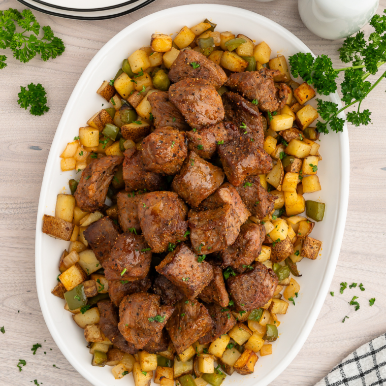 Plate of air fryer steak bites and potatoes garnished with fresh parsley