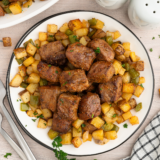 Juicy medium-rare sirloin steak bites and crispy roasted potato cubes served on a white plate
