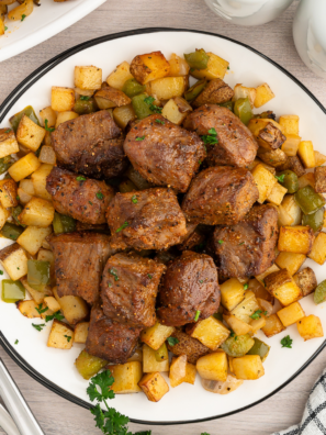 Juicy medium-rare sirloin steak bites and crispy roasted potato cubes served on a white plate