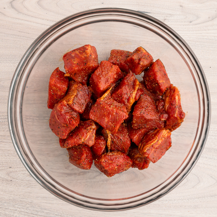 Cubed sirloin steak tossed with olive oil, garlic powder, and smoked paprika in a mixing bowl