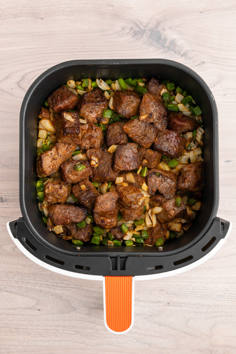 Close-up of air fryer steak bites and potatoes on a plate with a fork lifting a piece of medium-rare sirloin