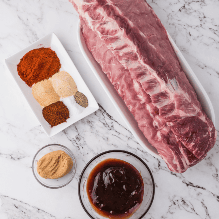 Ingredients for baby back ribs in the oven: ribs, dry rub spices, and barbecue sauce