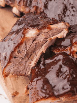 Baby back ribs in the oven glazed with barbecue sauce on a white plate
