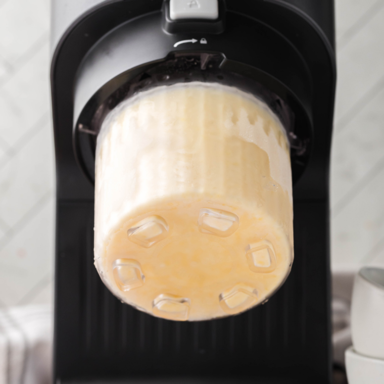 Freshly spun vanilla ice cream in a Ninja Creami pint with a well made in the center.