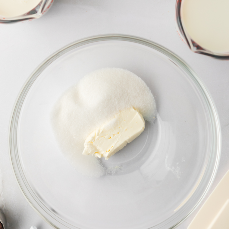 Cream cheese and sugar whisked into a smooth paste in a glass bowl, the first step in Ninja Creami Blue Bell mint chocolate chip ice cream.
