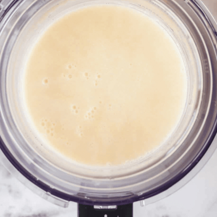 Pouring sweet cream base into a Ninja Creami pint container below the max fill line