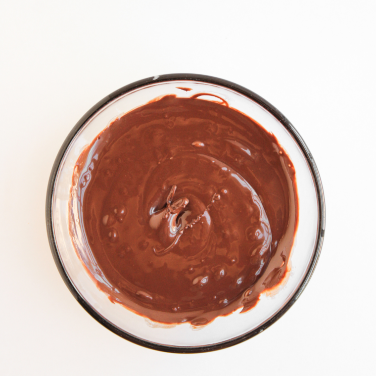Smooth melted chocolate in a glass microwave safe bowl, ready for dipping apple slices