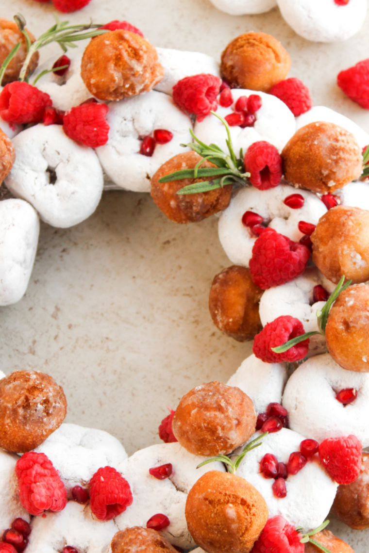 Pomegranate seeds sprinkled over a donut wreath with fresh rosemary sprigs tucked into the gaps