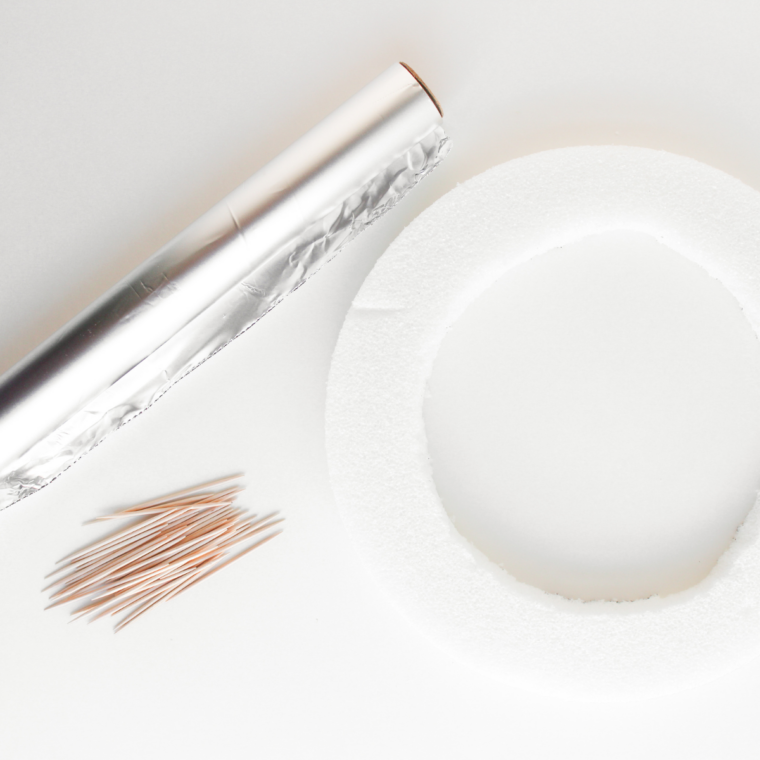 Foil and wreath with toothpicks on kitchen table.