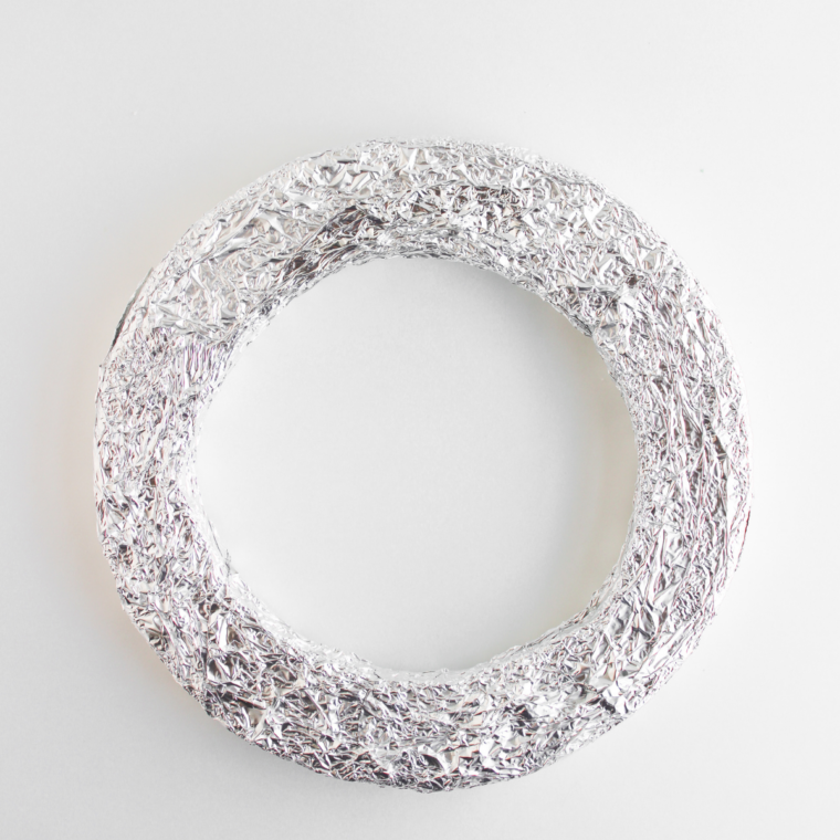 Round foam wreath form completely wrapped in aluminum foil, ready for donuts