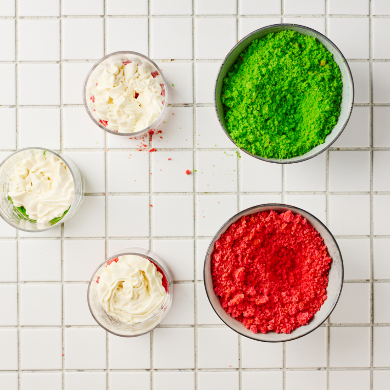 Crumbled red velvet and green vanilla cake in separate bowls for a Christmas trifle