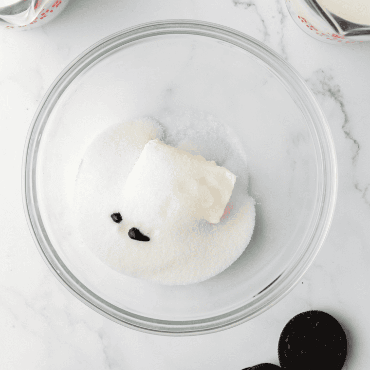 Whisking cream cheese and sugar into a smooth green mint ice cream base in a glass bowl